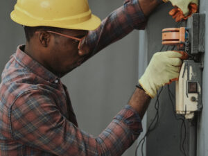Electrician in safety gear working on an electrical panel with modern tools