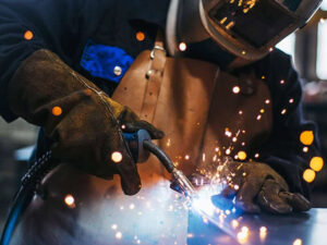 Worker performing hot works task with sparks, highlighting welding and fire safety risks