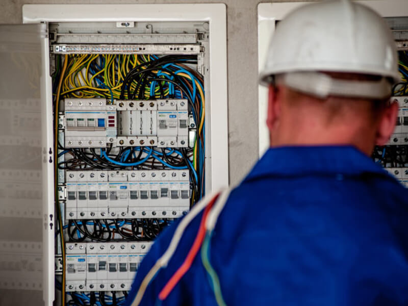 Licensed electrician inspecting a residential electrical breaker panel in Massachusetts